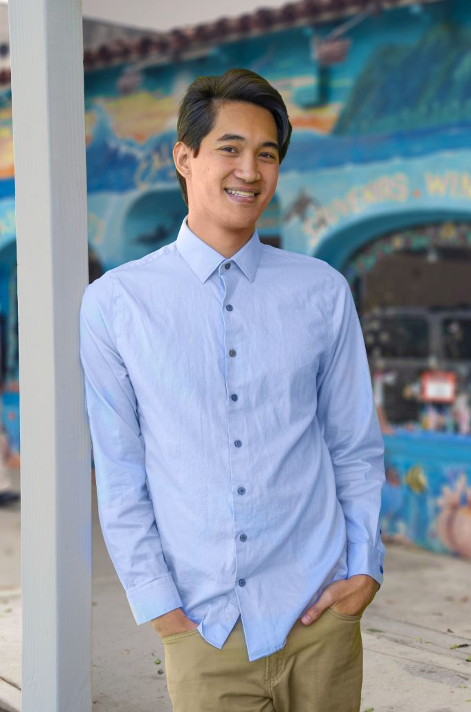 A photo of Christophe Ngo standing in outside of his BeachCAT Counseling office in Seal Beach, California looking happy and relaxed before talking to his clients to help with anxiety, stress and burnout, life transitions, and identity.